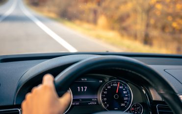 Steering wheel in a car close up, high speed driving on the road. Driving on the highway seen by the eyes of woman, steering wheel in a car close-up, high speed driving on the road, copy space.